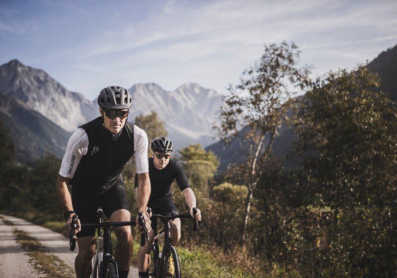 Zwei Rennradfahrer fahren bergauf mit Bergpanorama im Hintergrund. | © Kottersteger Manuel